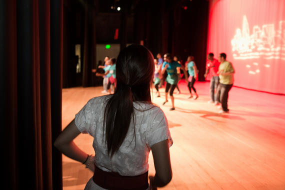 Girl watching teenagers rehearsing on stage